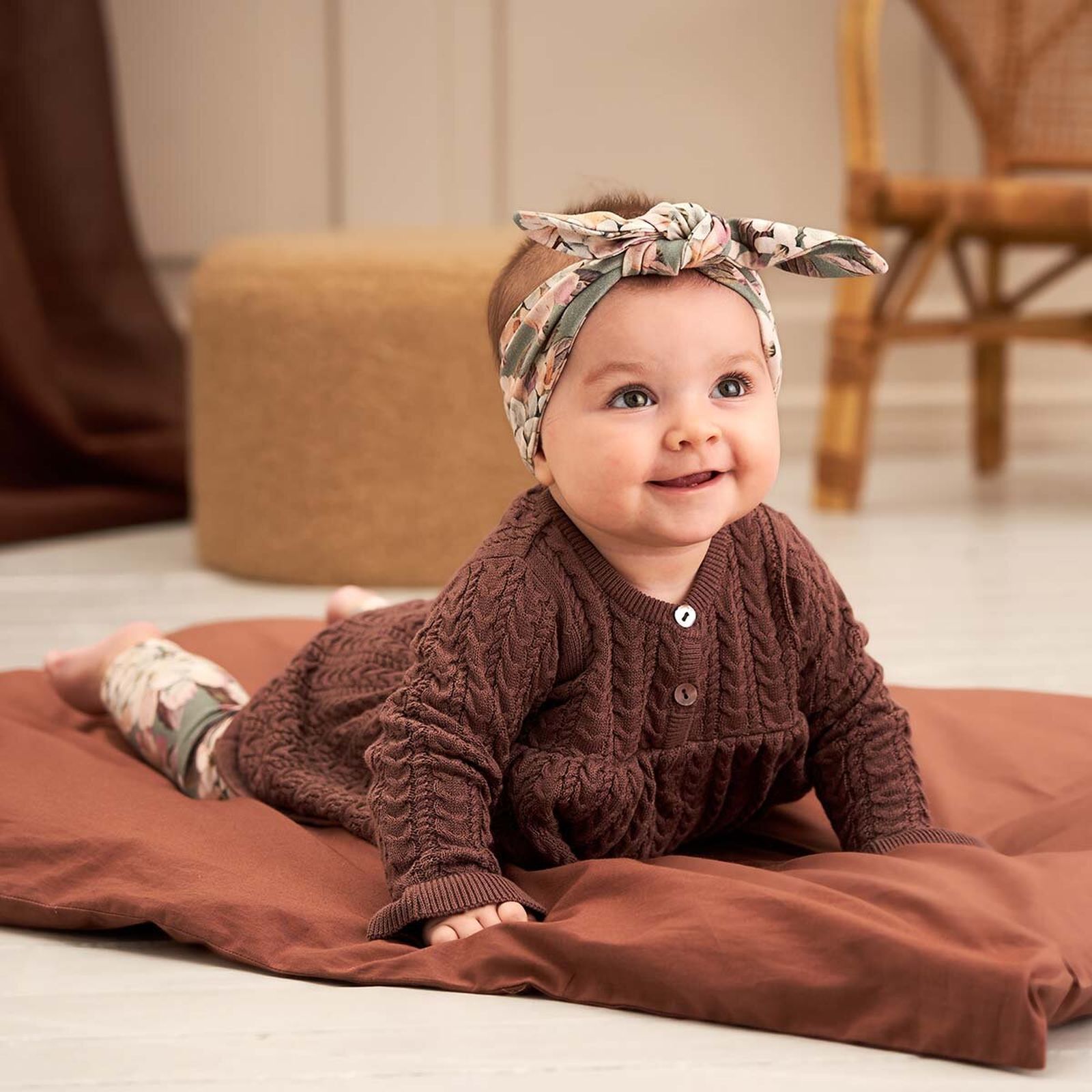 Baby-Mädchen in einem braunen Strickkleid und eine hübschen Kopfband